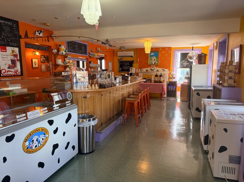 The inside of Morton’s Moo: orange walls, a long wooden counter with orange stools and cow-print freezers
