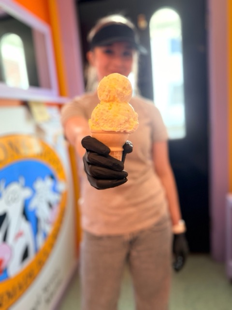 A server in gloves holding out a double-scoop cone